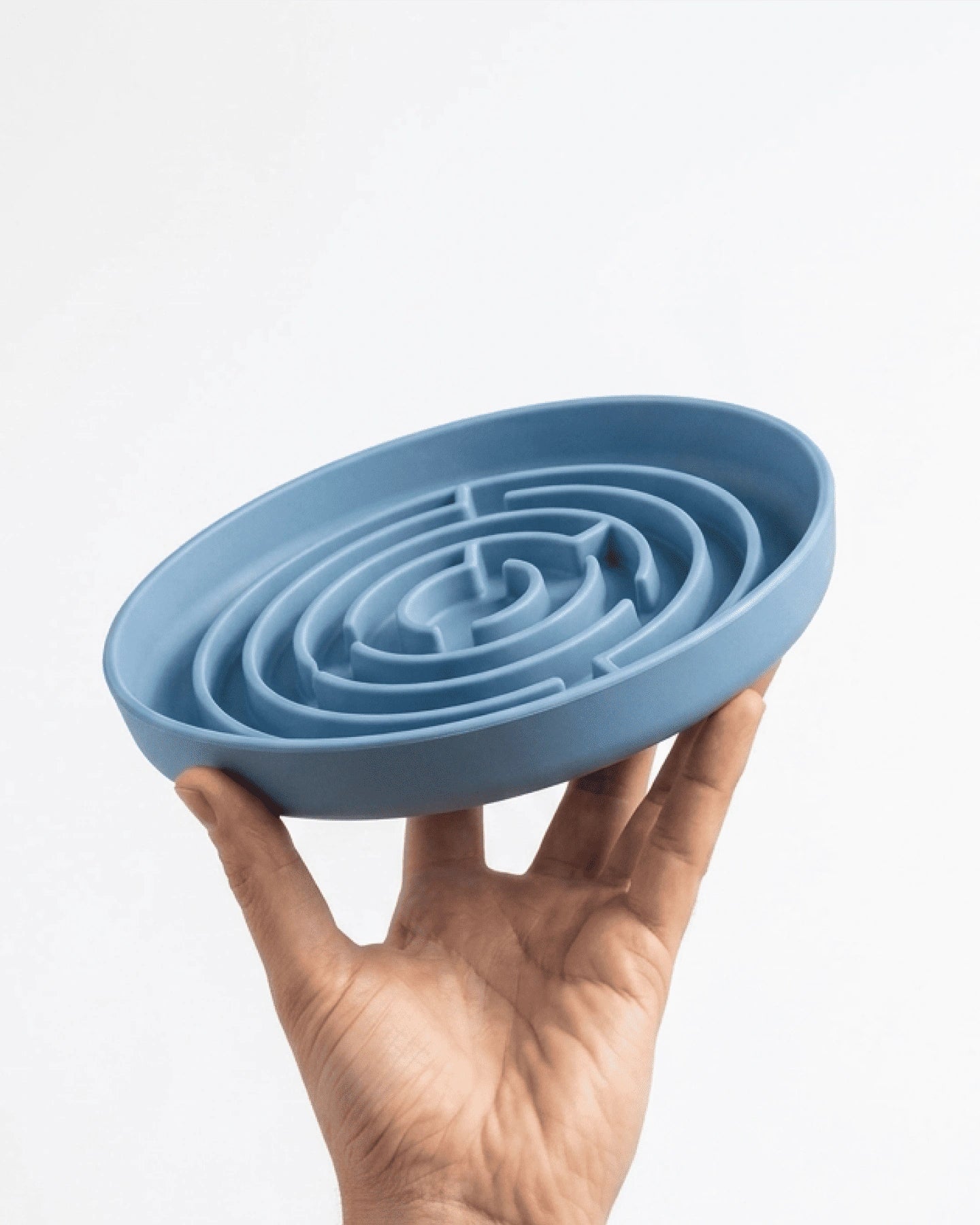 Hand holding a blue labyrinth silicone mat against a white background