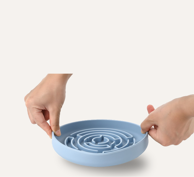 Blue maze puzzle bowl of chonky paws held by two hands on a white background