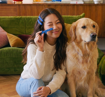 Woman holding a blue toy with a dog sitting next to her on a green couch.