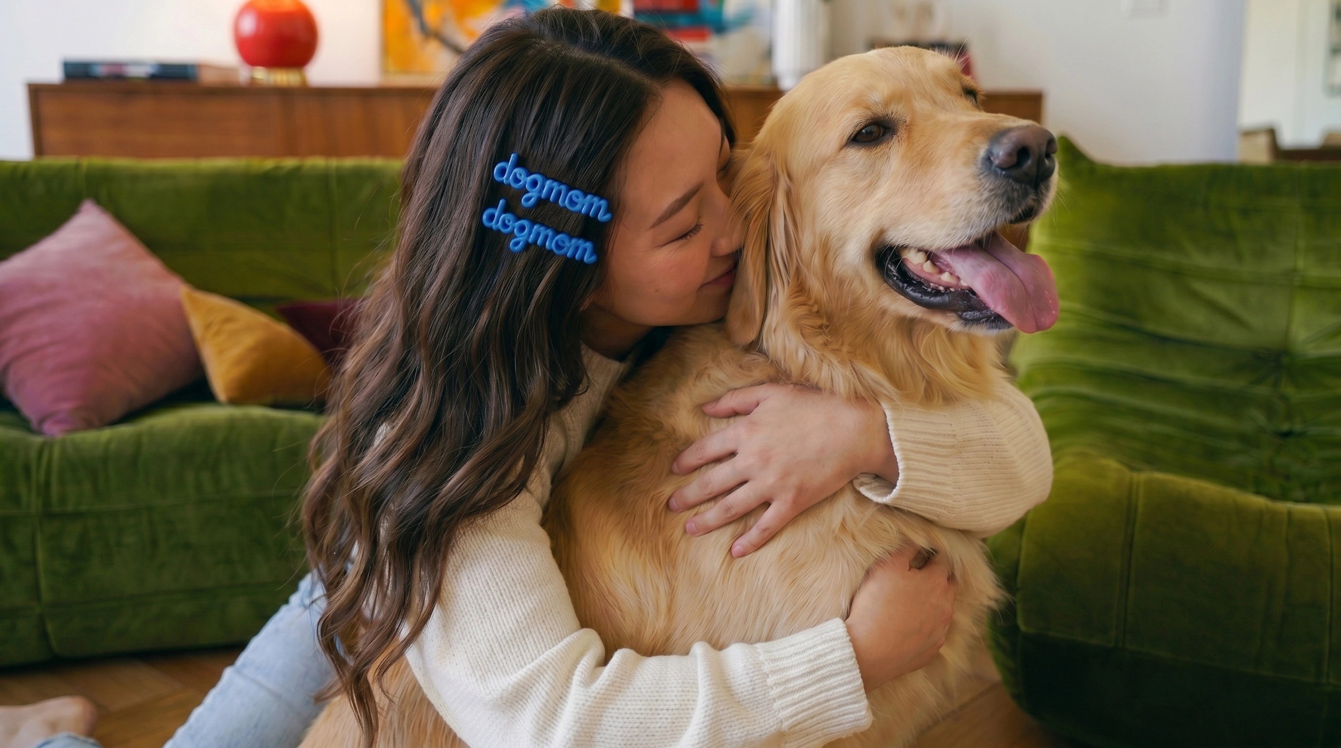 Woman hugging a golden retriever in a living room with colorful cushions on a green couch.
