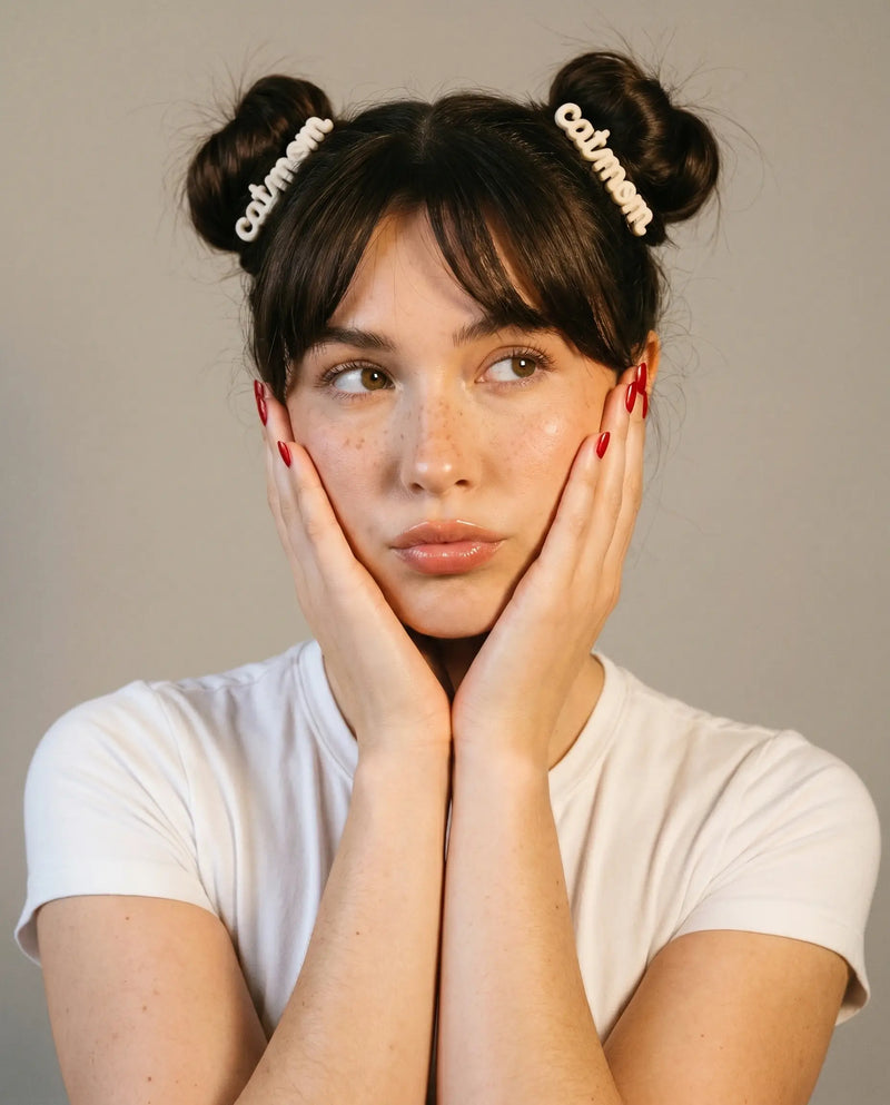 Woman with styled hair wearing 'Catwoman' headbands against a neutral background